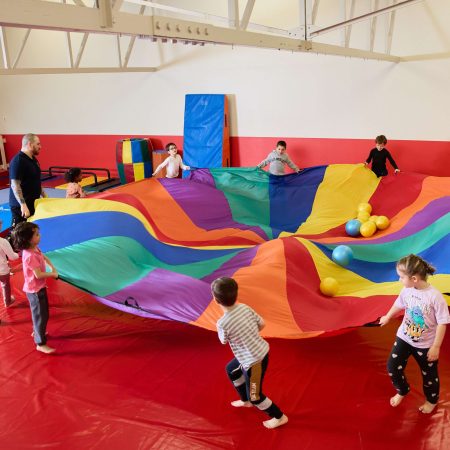 Enfants souriants sur un parcours de motricité encadrés par des animateurs, participant à un stage vacances Toup’ti Gym